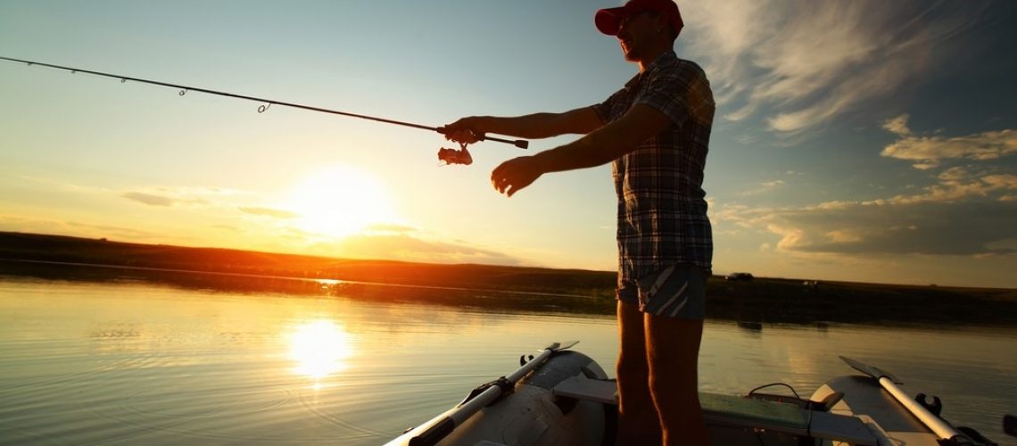 Man fishing from a boat at sunset