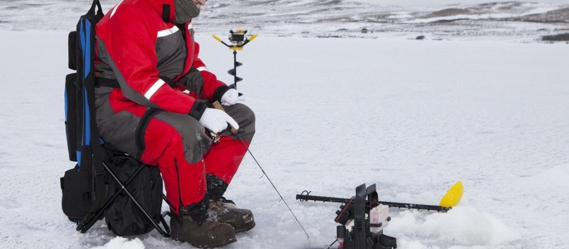 Man ice fishing on a cold winter day.